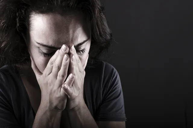 A woman is holding her hands to her face.