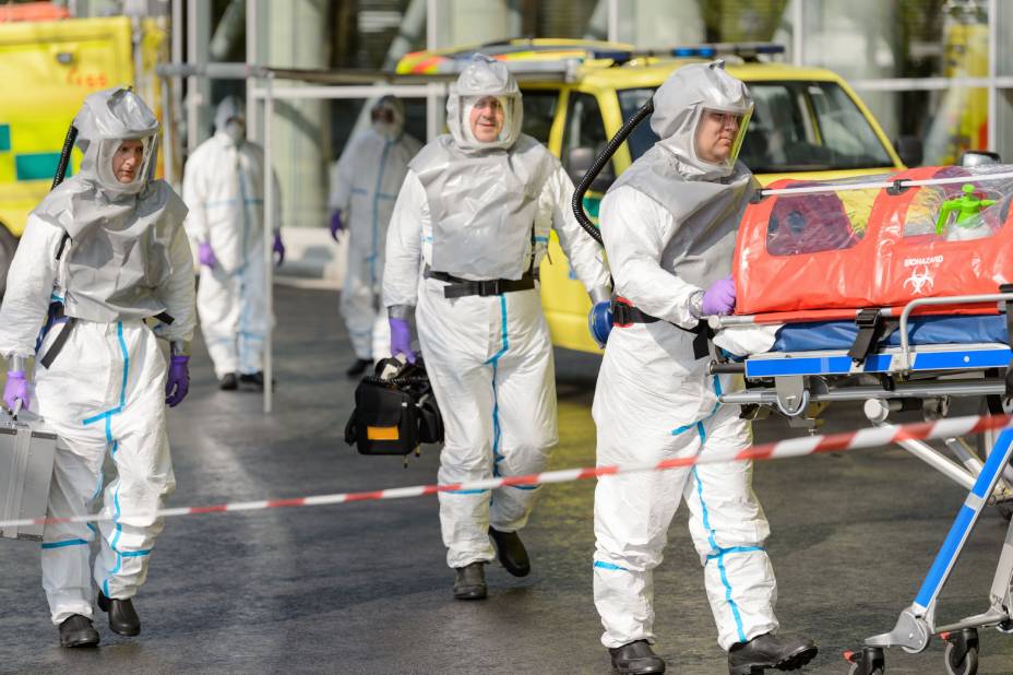 A group of people in hazmat suits walking down the street.
